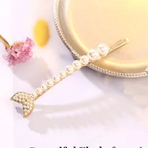 Elegante fermaglio dorato con design a coda di pesce e perle bianche su fiori