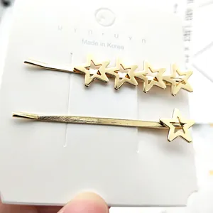 Dettaglio di due fermagli per capelli dorati a forma di stella su carta bianca