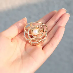 Détail macro d'une pince à cheveux rose dorée avec perle et pétales ajourés