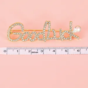 Golden Goodluck letter brooch with sparkling crystals and pear-shaped rhinestone