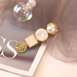 Primer plano de pasador dorado con perlas y resina sobre fondo de tela suave y elegante