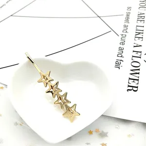 Dettaglio della molletta dorata con stelle a cinque punte su un piatto a cuore bianco