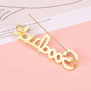 Golden 'Goodbye' rhinestone letter brooch with elegant pin backing on pink texture