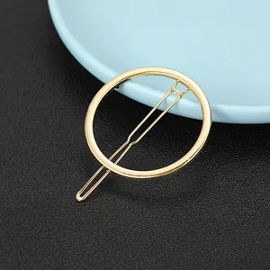 Close-up of minimalist golden alloy circular hair clip with smooth polished metal finish