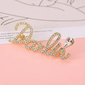 Detail of a gold letter brooch with sparkling rhinestones and a large pear-cut zircon