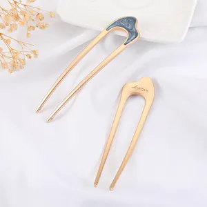 U-shaped gold hair pins with blue enamel and Anemone engraving on white fabric