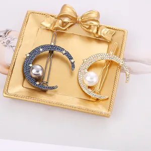 Elegant crescent moon hair clips with sparkling rhinestones and delicate pearls in a gold tray