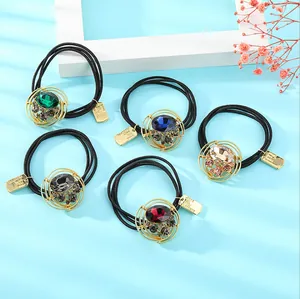Detalle de 5 gomas de pelo con pedrería de colores y adornos dorados sobre fondo azul