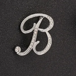 Primer plano de broche letra B plateado con cristales brillantes sobre cuero negro
