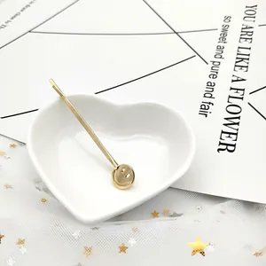 Dettaglio di un fermaglio per capelli dorato con faccina su piatto a forma di cuore