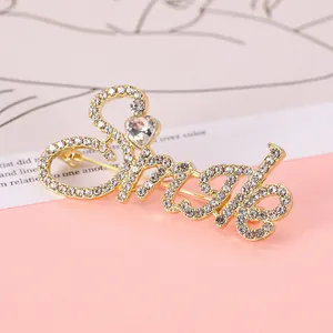 Detailed view of the gold Smile letter brooch featuring sparkling rhinestones and a heart