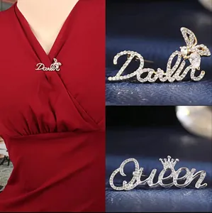 Macro detail of Darlin and Queen crystal brooches with bow and crown accents