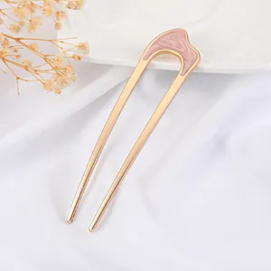 Elegant U-shaped gold hair pin with pink marble texture on white silk background