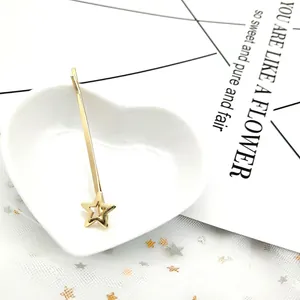 Dettaglio di un fermaglio per capelli a stella dorata su un piatto di ceramica a cuore