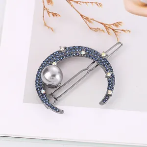 Detailed view of crescent moon hair clip with blue rhinestones and a grey pearl inlay