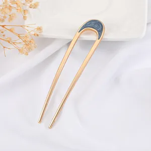 Minimalist U-shaped gold hairpin with marble-pattern enamel on elegant white fabric