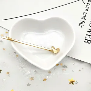 Vista dettagliata di un fermaglio per capelli dorato con motivo a cuore su vassoio bianco