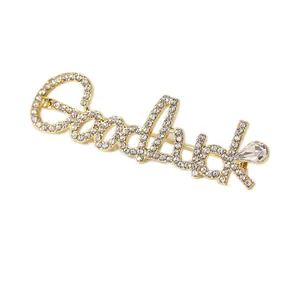 Golden Goodluck brooch with crystal rhinestones and a teardrop pendant on white background