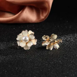 Macro view of white daisy brooch featuring pearl center and gold plated metal clasp