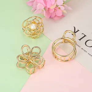 Vue détaillée de trois pinces à cheveux dorées en forme de fleur avec perles