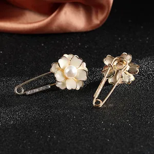 Elegant camellia flower brooches with white enamel petals and pearls on black background