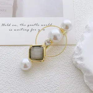 Detail view of a gold alloy hairpin with white pearls and gray cat-eye stone