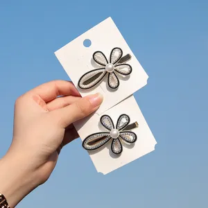 Dettaglio di fermagli per capelli a fiore con perle bianche e strass scintillanti