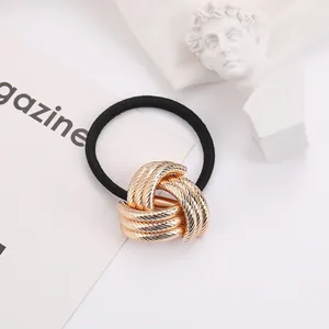 Detail of a golden spiral metal knot on a black elastic hair tie with white art decor