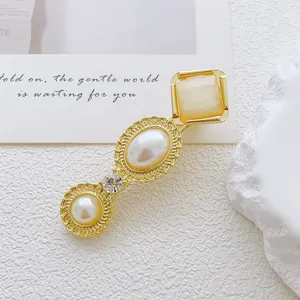 Detail of vintage gold alloy hair clip with cat eye stone and pearls on white background