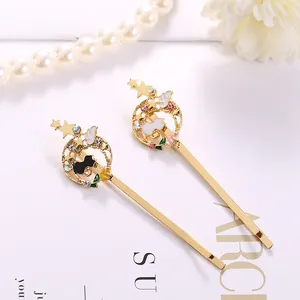 Detailansicht goldener Haarspangen mit Mond, Stern und Katzenmotiven sowie Kristallen