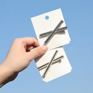 Primo piano di eleganti fermagli per capelli a X neri con strass e perle su cartoncino