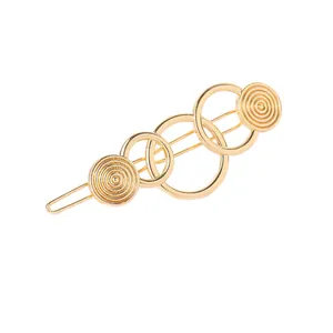 Minimalist gold metal hair clip with geometric interlocking circles design on white background