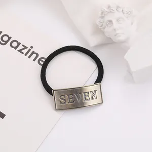 Minimalist black elastic hair tie with vintage bronze SEVEN engraved metal plate