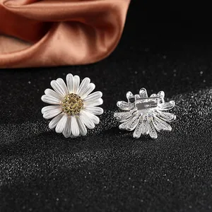 Macro detail of daisy pins with white enamel petals and yellow crystal pavé centers