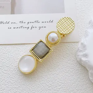 Detailed view of a gold hair clip with square opal resin stone and pearl accents