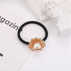 Close-up of a shell hair tie with gold accents and a central pearl detail