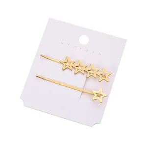 Set di due fermagli per capelli dorati a forma di stella su carta da esposizione bianca