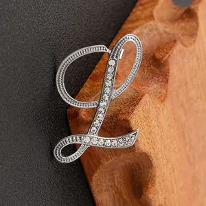 Detalle macro de broche letra L de plata con pedrería de diamantes de imitación