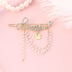 Elegant gold bow hair clip with sparkling rhinestones and dangling pearl tassels