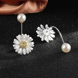Detail of daisy flower earrings with white petals, yellow core, and a round pearl