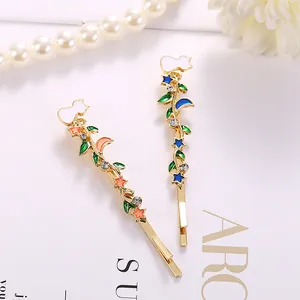 Detailansicht eleganter vergoldeter Haarklammern mit Emaille-Blatt und Stern-Mond-Muster