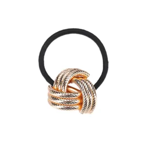 Detailed close-up of golden metallic twist knot on elastic hair tie with texture