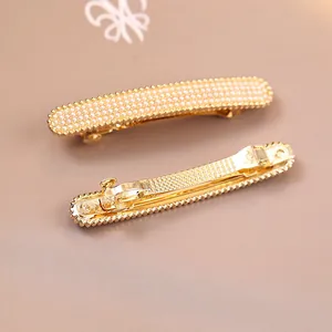 Dettaglio dei fermagli per capelli con perle oro champagne e design a molla
