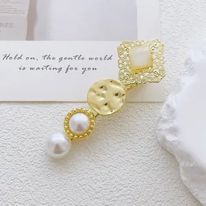 Detailed shot of a gold alloy hair clip featuring cat's eye stone and white pearls