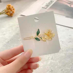 Close-up of elegant floral hair clip with cream yellow petals on a white display card