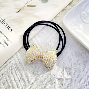 Close-up of elegant hair tie with pearl-encrusted bow and sparkling rhinestone details