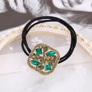 Detalle de dije dorado con cristales en gomas de pelo negras de alta elasticidad