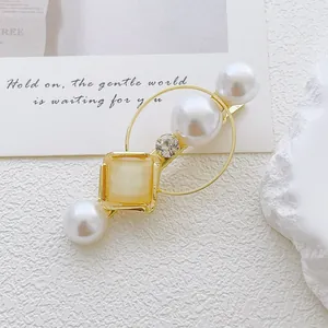 Detail of gold hair clip with white pearls, crystal, and cat eye stone on white texture