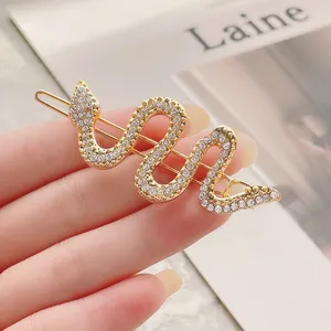 Pasador de pelo de serpiente dorado con brillantes pedrería en fondo minimalista