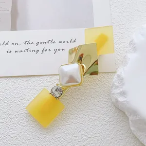 Detail of geometric hair clip with yellow matte cubes, gold rhombus and pearl inlay